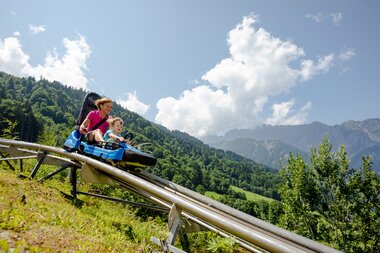 Eine Frau und ein Kind fahren auf einer Sommerrodelbahn den Berg hinunter | © Golm Silvretta Lünersee Tourismus GmbH Bregenz, Stefan Kothner