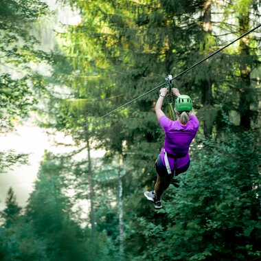 Frau die eine Seilrutsche hinunterrutscht im Wald | © Golm Silvretta Lünersee Tourismus GmbH, bobdo