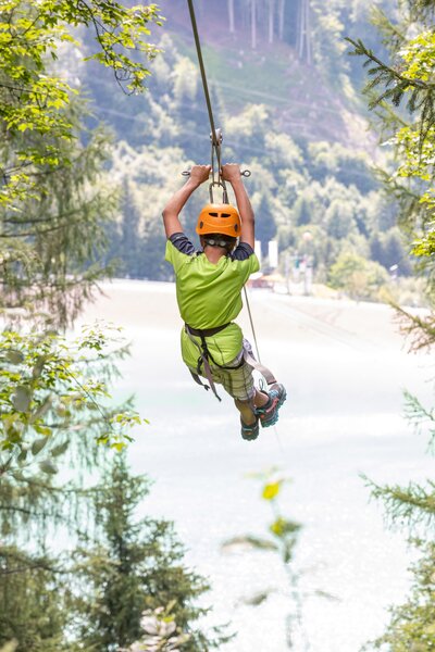 A boy flying over the Latschau reservoir attached to a 565 m long steel cable | © Golm Silvretta Lünersee Tourismus GmbH Bregenz, Stefan Kothner