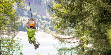 A boy flying over the Latschau reservoir attached to a 565 m long steel cable | © Golm Silvretta Lünersee Tourismus GmbH Bregenz, Stefan Kothner