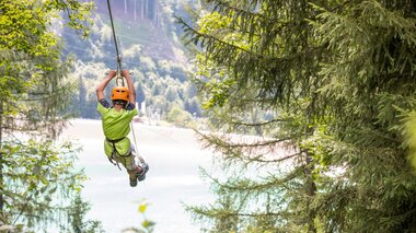 A boy flying over the Latschau reservoir attached to a 565 m long steel cable | © Golm Silvretta Lünersee Tourismus GmbH Bregenz, Stefan Kothner