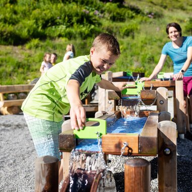 Mutter und Sohn, die gemeinsam beim Wasserspiel auf Golmis Forschungspfad die Kraft des Wassers entdecken | © Golm Silvretta Lünersee Tourismus GmbH Bregenz, Stefan Kothner