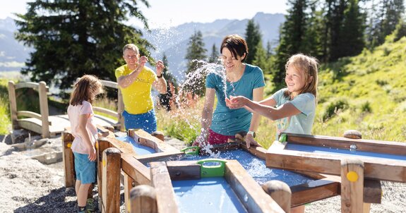 Father and mother discovering the power of water together with their two daughters while playing water games on Golmis Forschungspfad | © Golm Silvretta Lünersee Tourismus GmbH Bregenz, Stefan Kothner