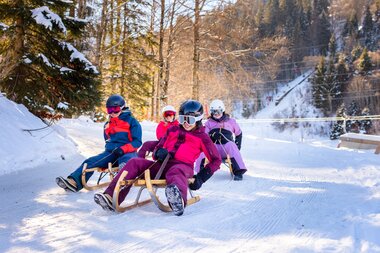 Four friends tobogganing down the toboggan run on the Erlebnisberg Golm together | © Golm Silvretta Lünersee Tourismus GmbH Bregenz, Stefan Kothner