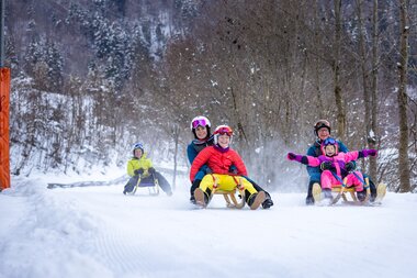 A family of five tobogganing down the toboggan run on the Erlebnisberg Golm | © Golm Silvretta Lünersee Tourismus GmbH Bregenz, Stefan Kothner