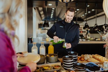 Mann der gerade Saft einschenkt am Frühstücksbuffet im Restaurant Feineck | © Golm Silvretta Lünersee Tourismus GmbH Bregenz, Philipp Schilcher